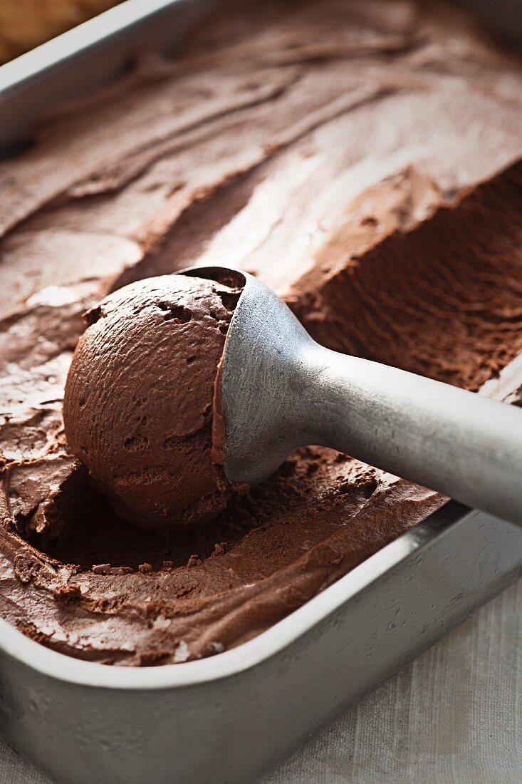 Schokoladeneiscreme im Behälter mit Eiskugelformer (Close Up)