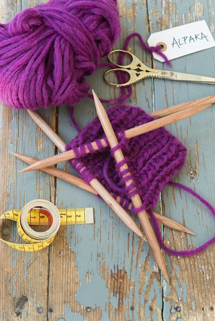 Strickarbeit aus violetter Alpaka Wolle mit Nadelspiel aus Holz