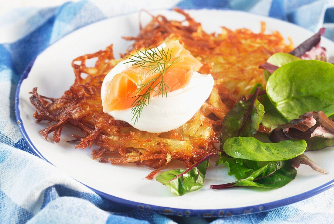 Potato cakes with sour cream and smoked salmon on a blue-and-white plate