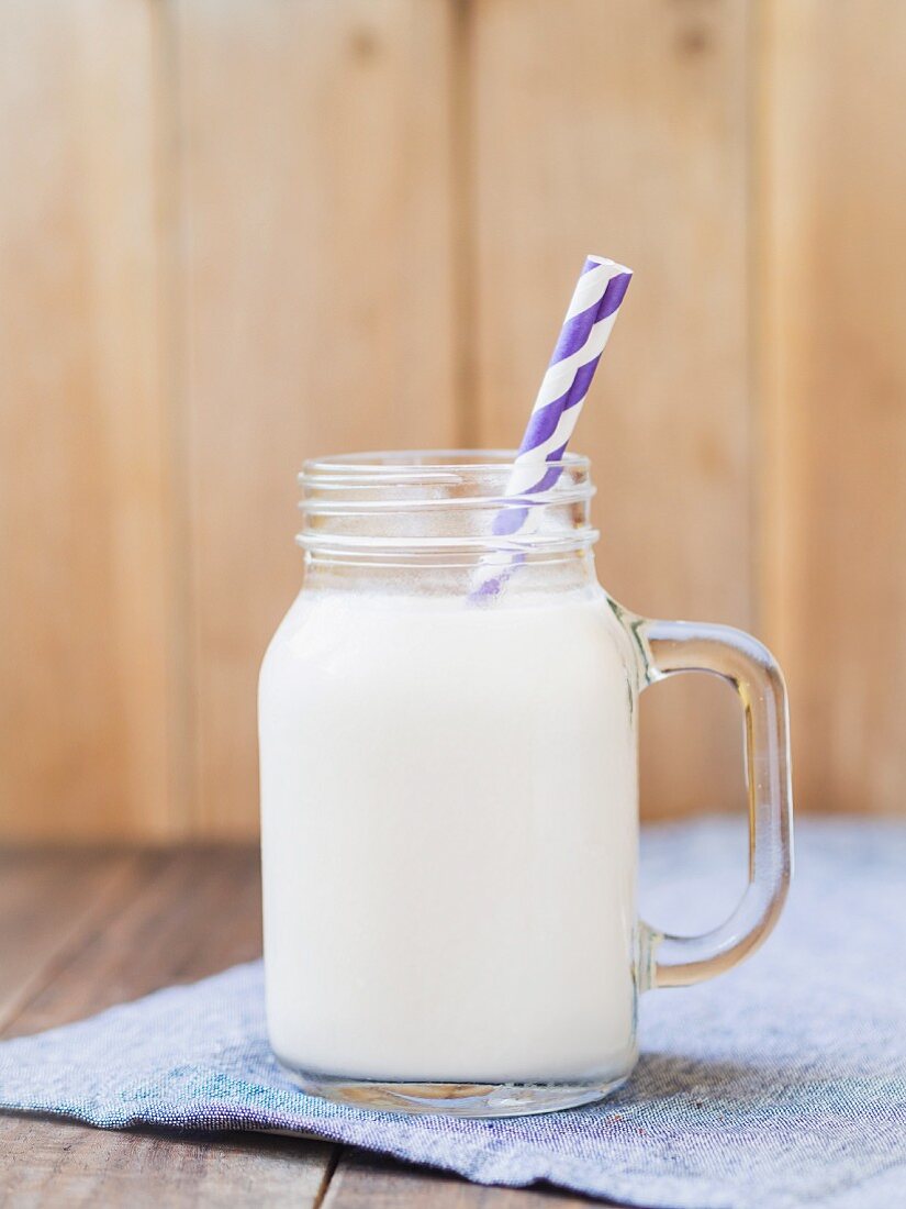 Homemade organic almond milk in a glass with a paper straw