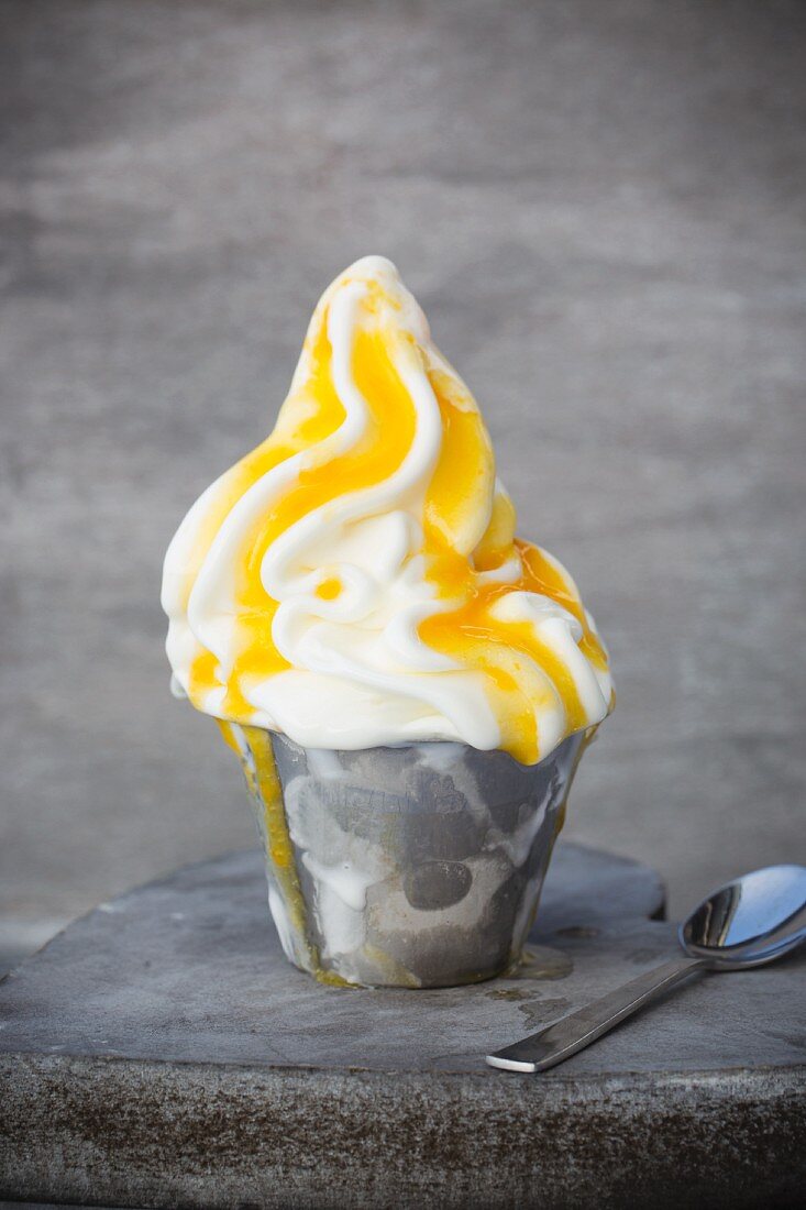 Frozen yoghurt in a metal cup with passion fruit purée