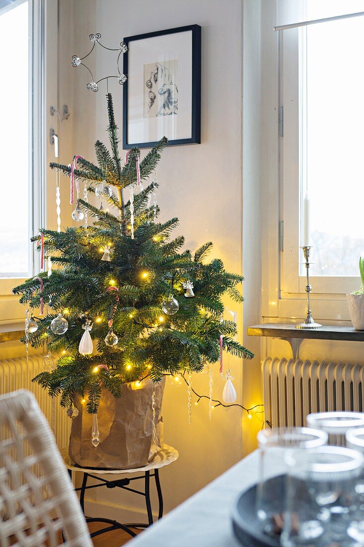 Mit Glasanhängern geschmückter Weihnachtsbäumchen in Zimmerecke