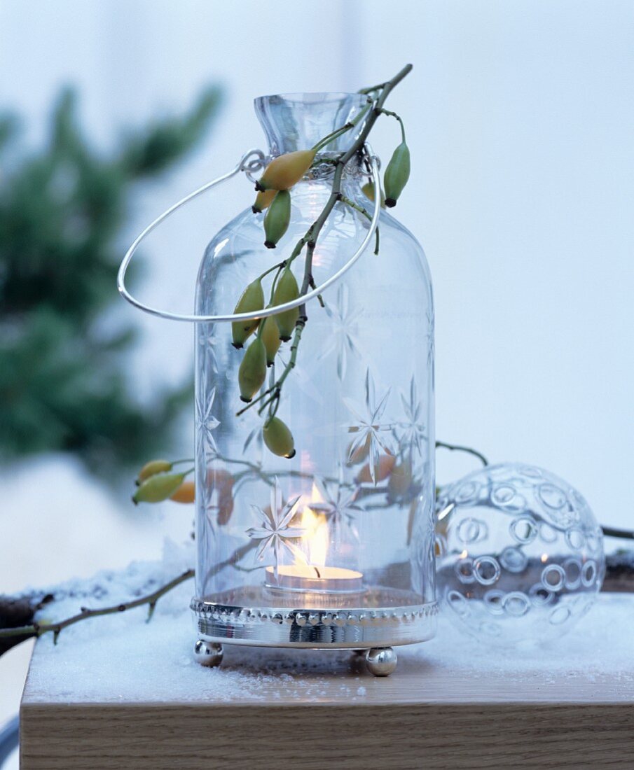 Windlicht aus Glas dekoriert mit Hagebuttenzweig