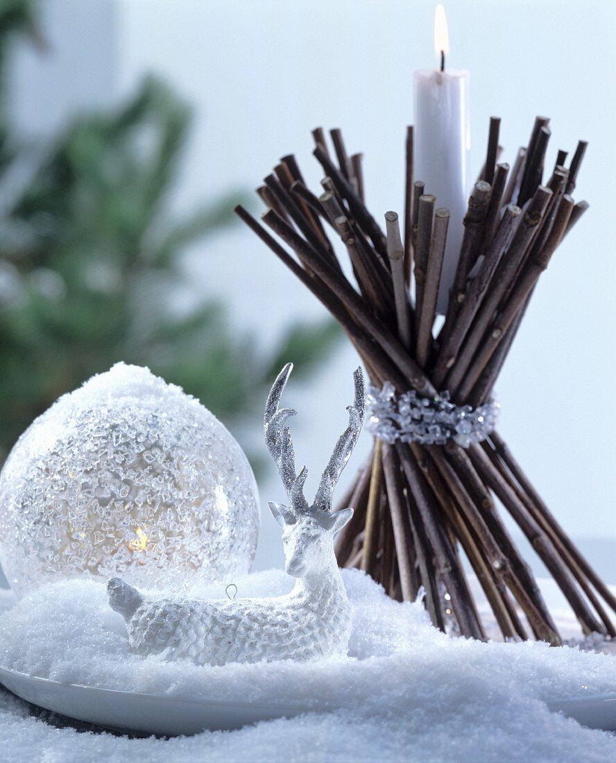 Weihnachtliche Deko mit Glaskugel, Rentierfigur und selbstgebasteltem Kerzenhalter aus gebündelten Zweigen
