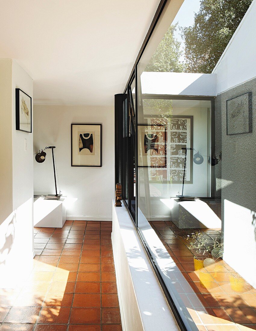 Reflections in glass façade of foyer with terracotta floor in modern bungalow