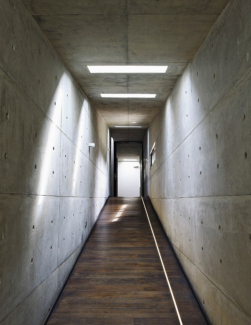Corridor with sloping floor and concrete walls and ceiling