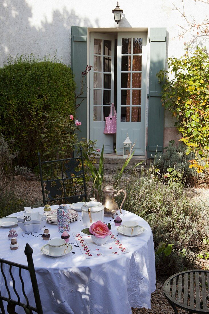 Set breakfast table in autumnal garden outside old country house with French windows