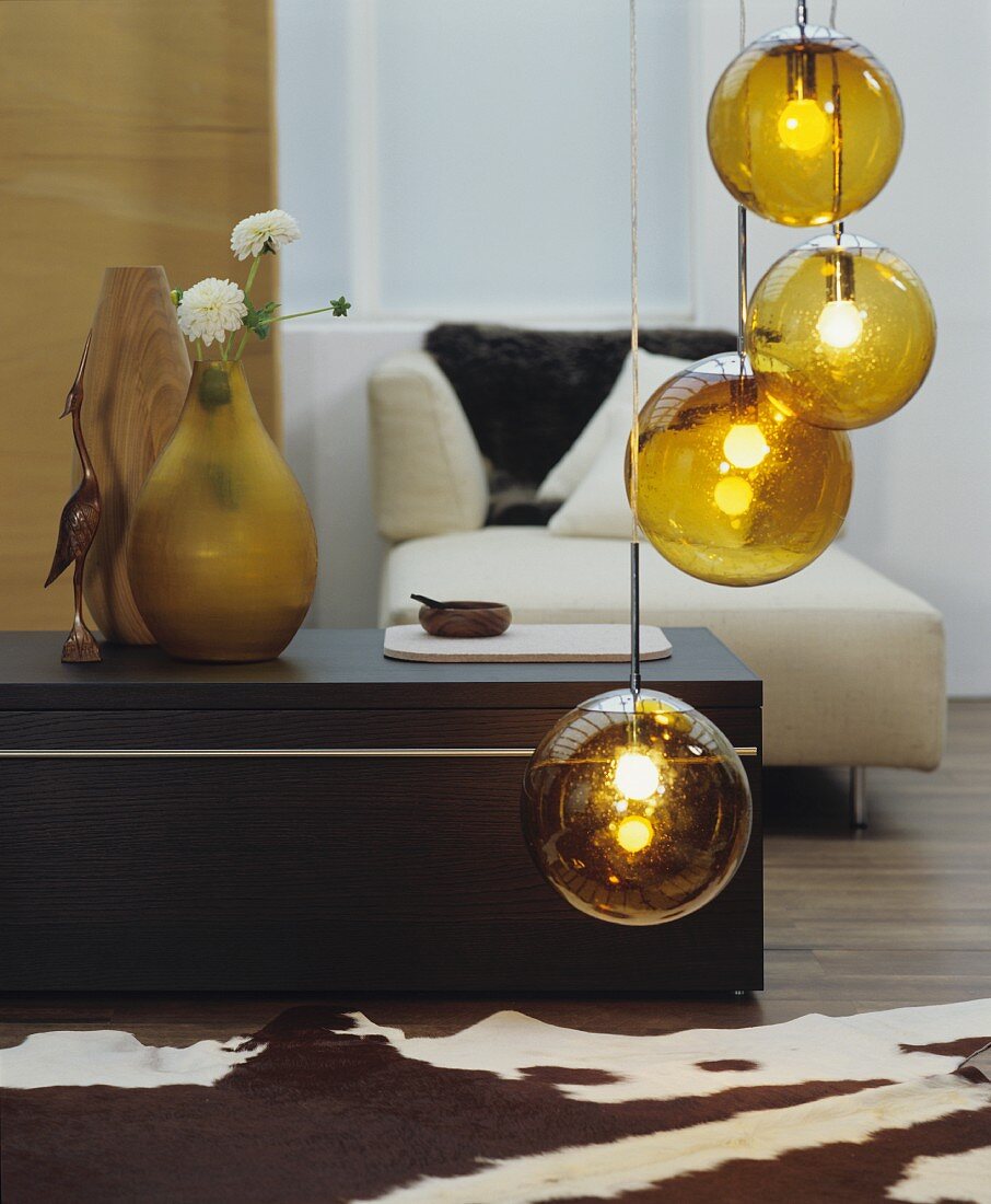 Gold spherical pendant lamps, animal-skin rug, coffee table and modern chaise in living room