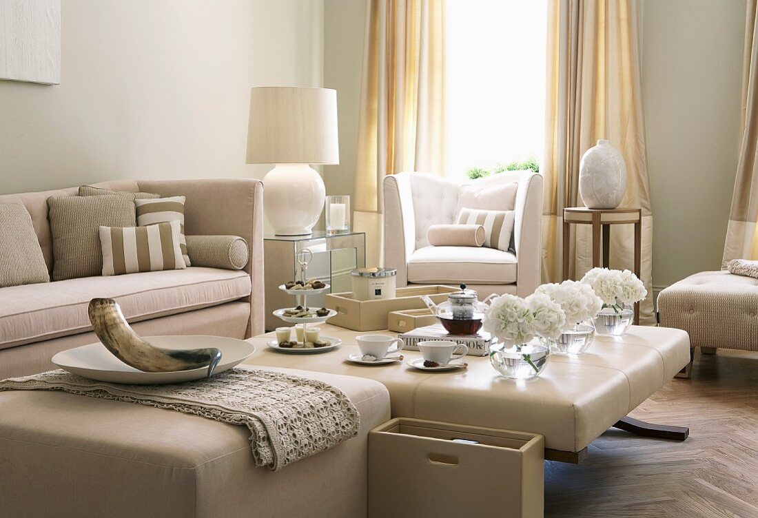 Tea service on ottoman and pale beige seating in traditional living room