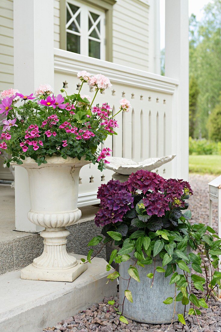 Amphore und Eimer mit Blumen vor einem Schwedenhaus