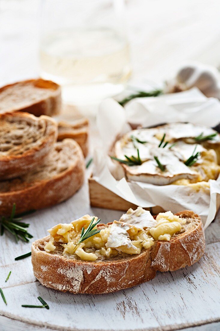 Baked cheese with rosemary and garlic on baguette slices