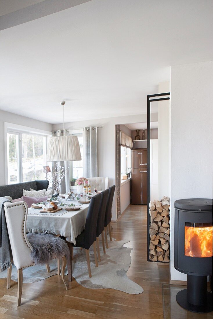 Set table, upholstered chairs, log burner and firewood store in dining room