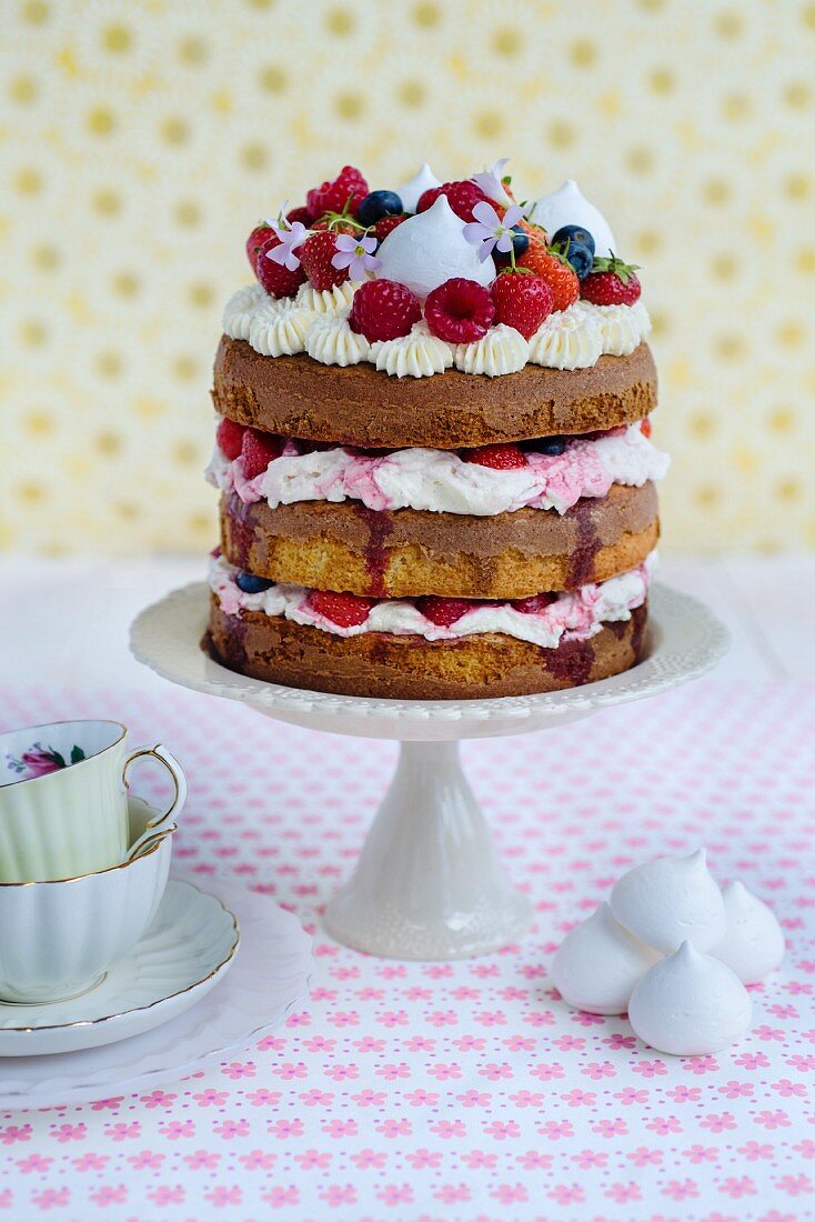 Eton-Mess-Schichtkuchen mit Erdbeeren, Himbeeren und Heidelbeeren auf Kuchenständer