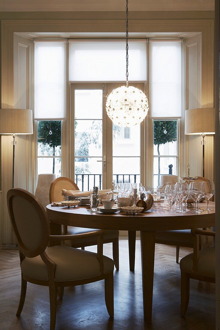 Spherical lamp above round exotic-wood table and English-style upholstered chairs