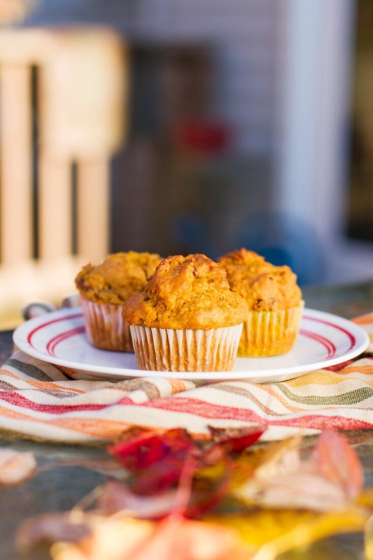 Vegane Kürbismuffins auf herbstlich gedecktem Gartentisch