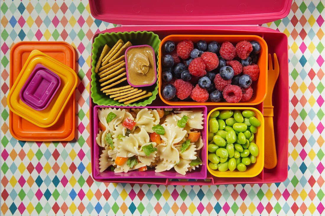 Pasta salad, beans, berries and crackers in a lunchbox