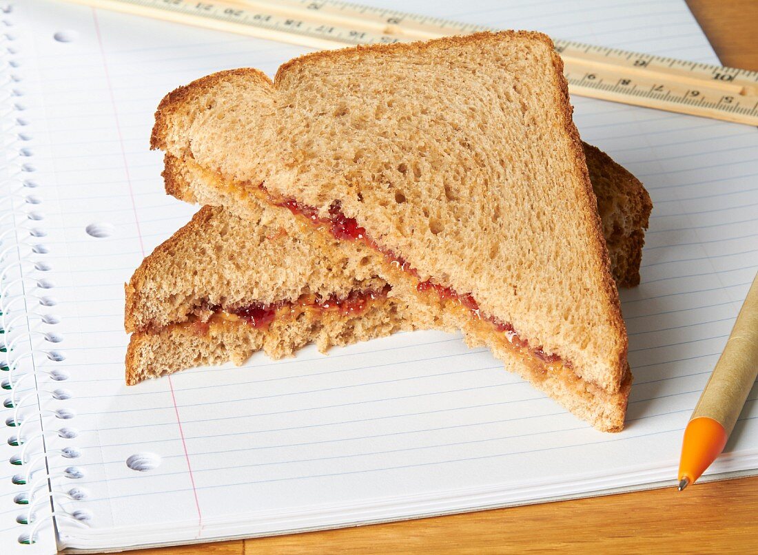 A peanut butter and jam sandwiches on a notebook