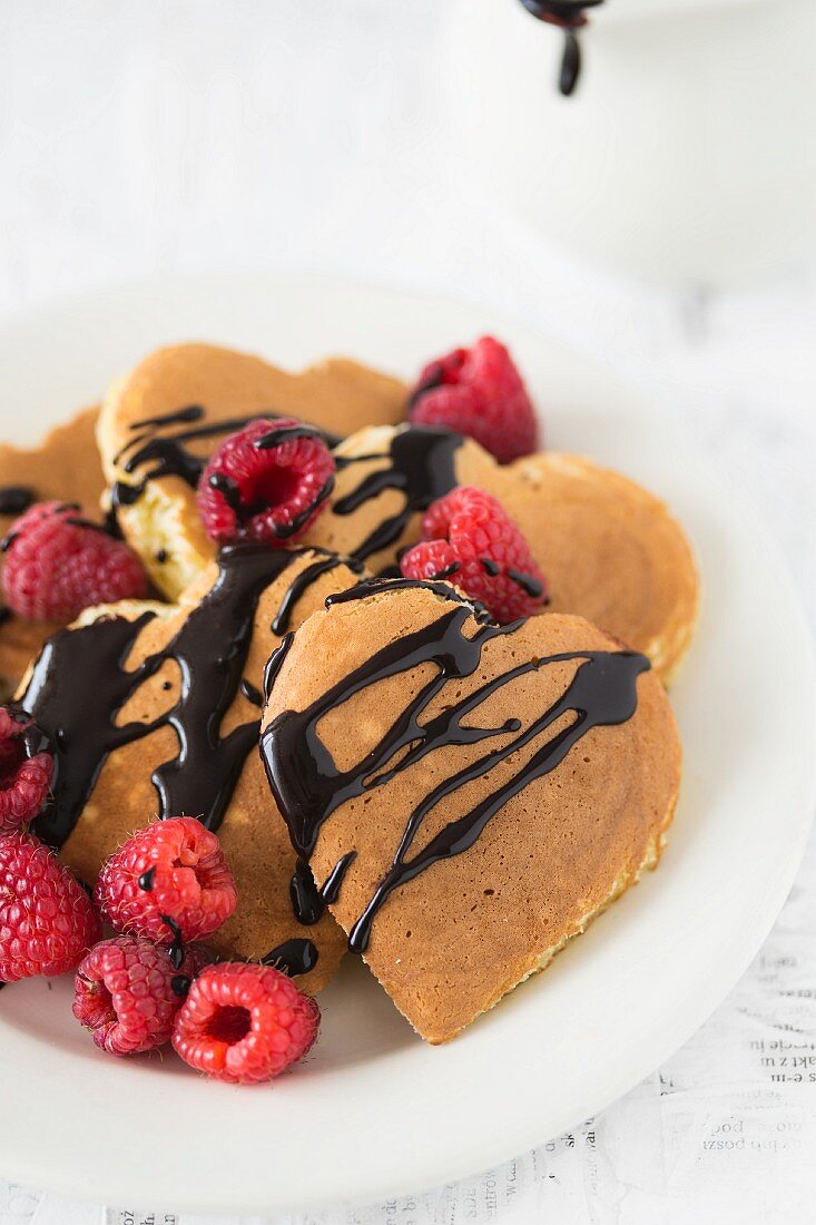 Heart-shaped pancakes with chocolate sauce and raspberries