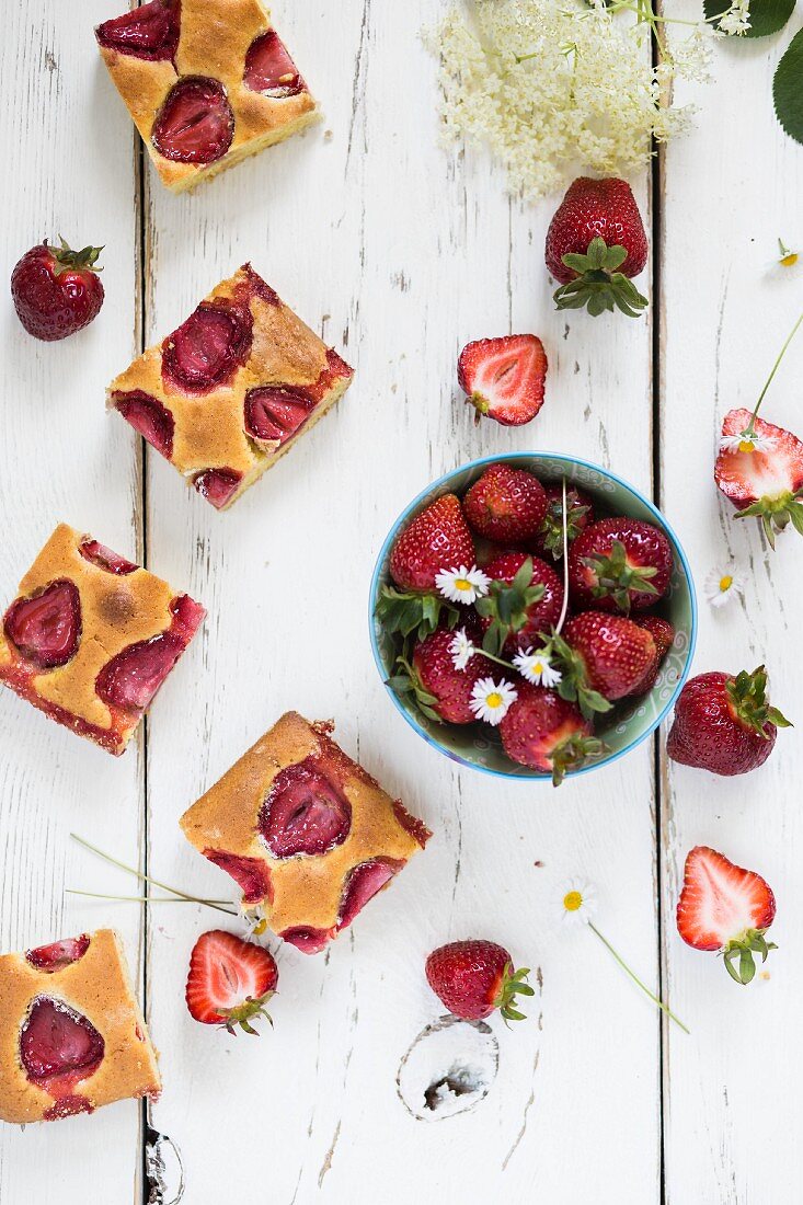 Slices of strawberry vanilla cake and a bowl of fresh strawberries