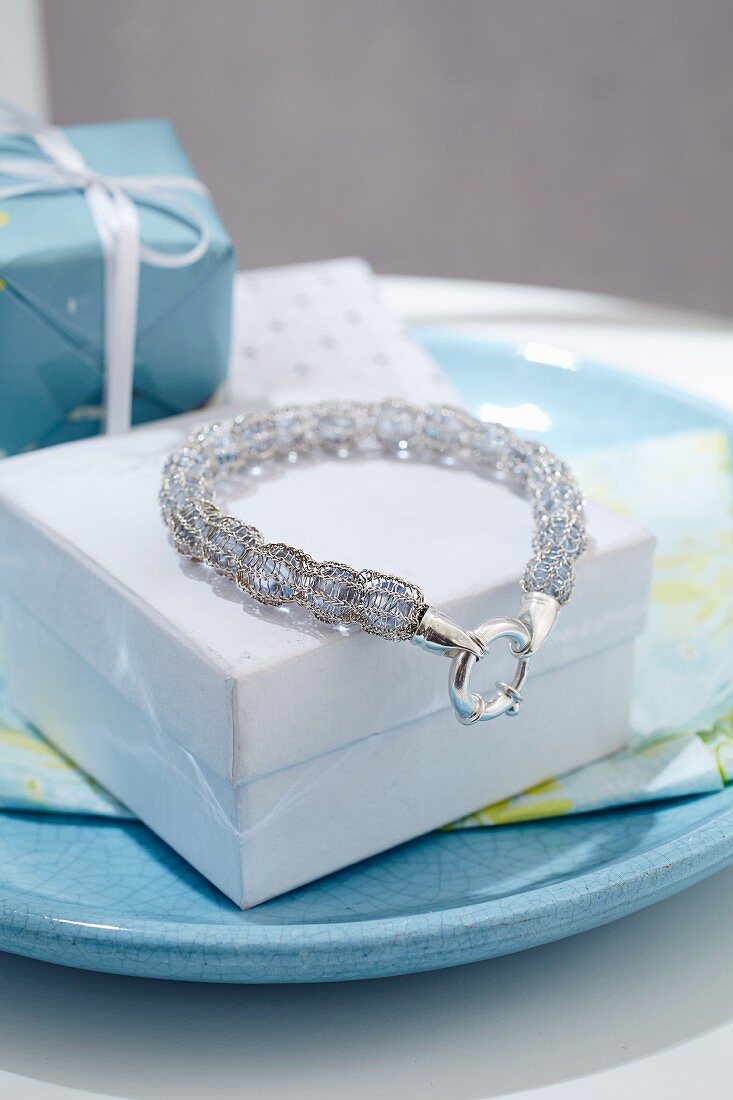 A beaded bracelet with a knitted encasing on a white box