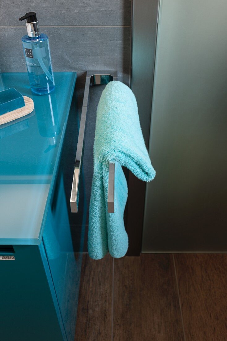 Türkises Handtuch auf Edelstahl Handtuchhalter neben Waschtisch in modernem Bad