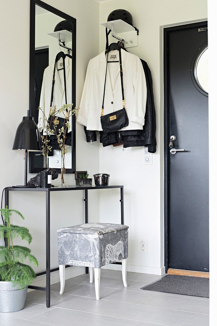 Delicate console table and coat rack in black and white foyer