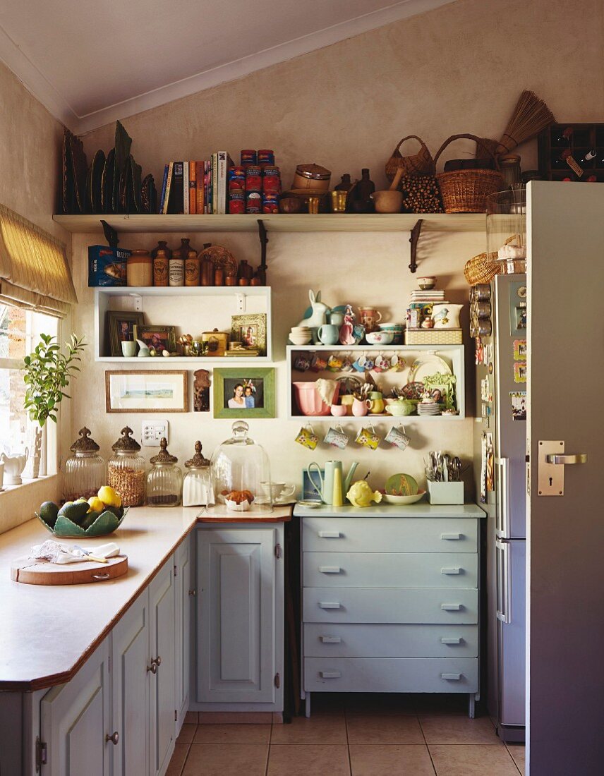 Well-filled, open-fronted, wall-mounted shelves in cosy kitchen