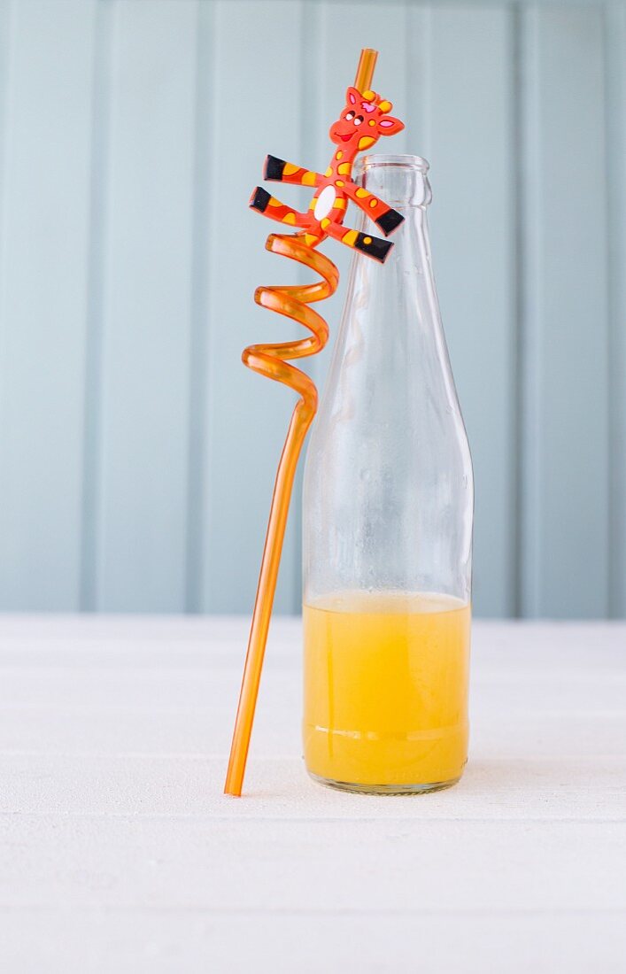 Orangenlimonade in Glasflasche und Strohhalm mit Giraffe