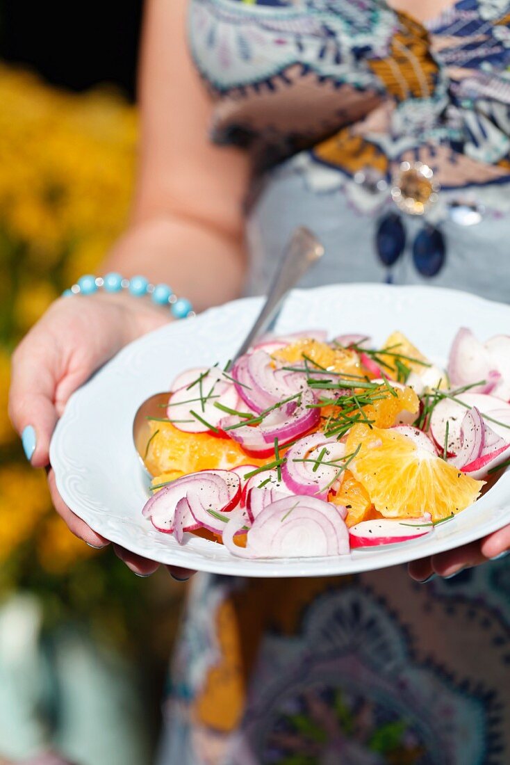 A woman carrying an orange and radish salad