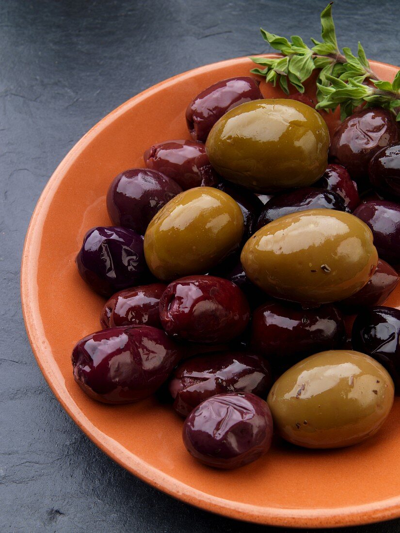 Oliven auf orangefarbenem Teller (Tapas)