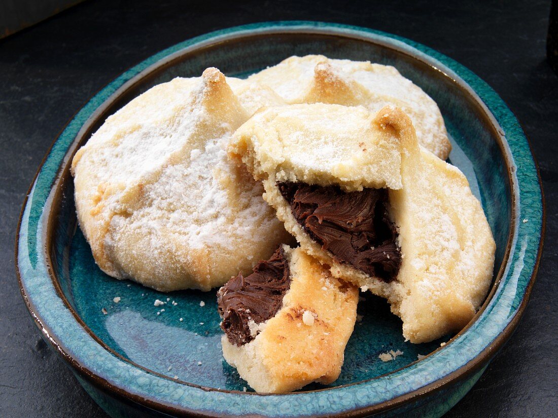 Shortbread cookies filled with chocolate dusted with icing sugar (broken)