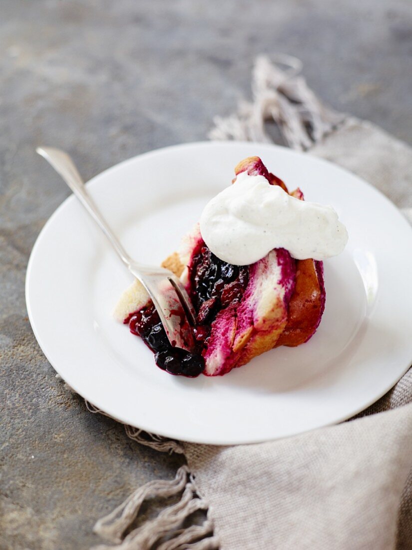 A slice of berry cake with whipped cream