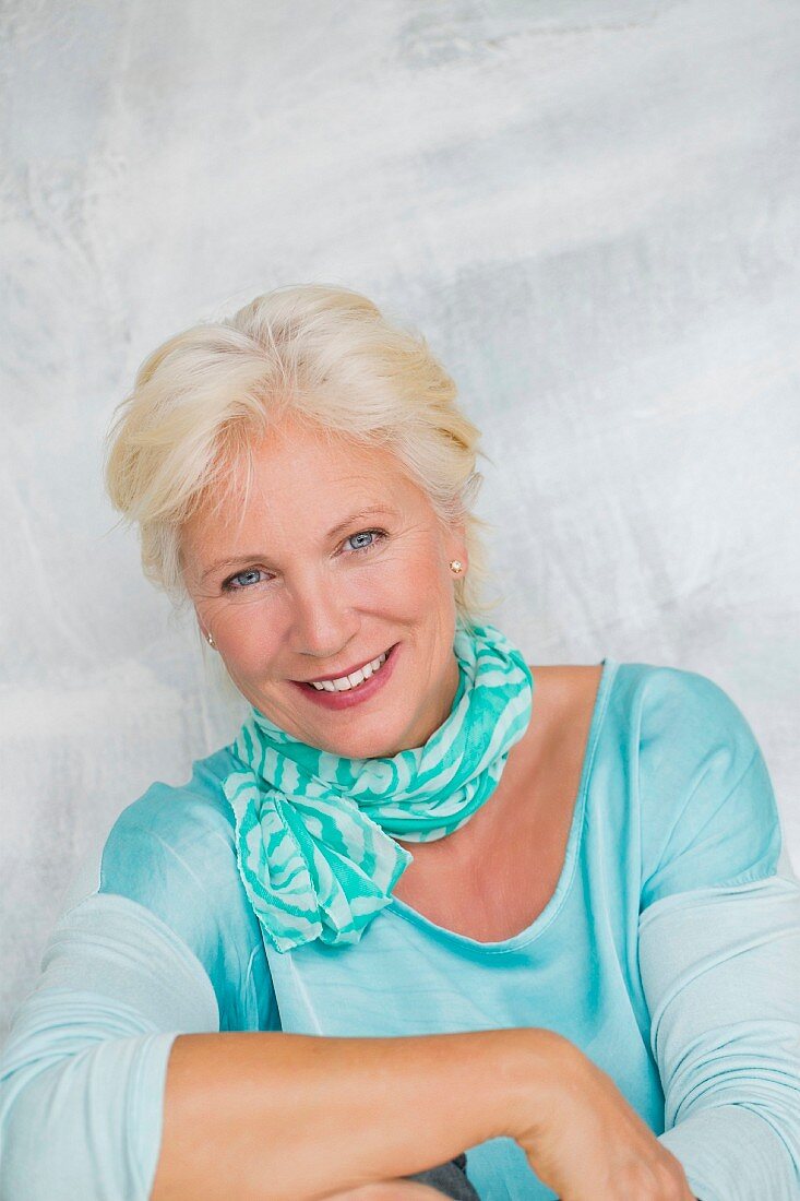 An older woman wearing a turquoise top and a scarf