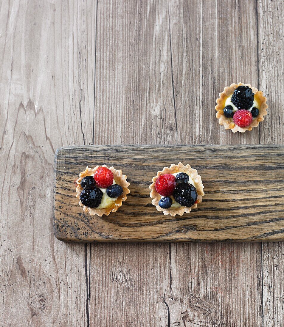 Organic mini berry tartlets on a wooden board