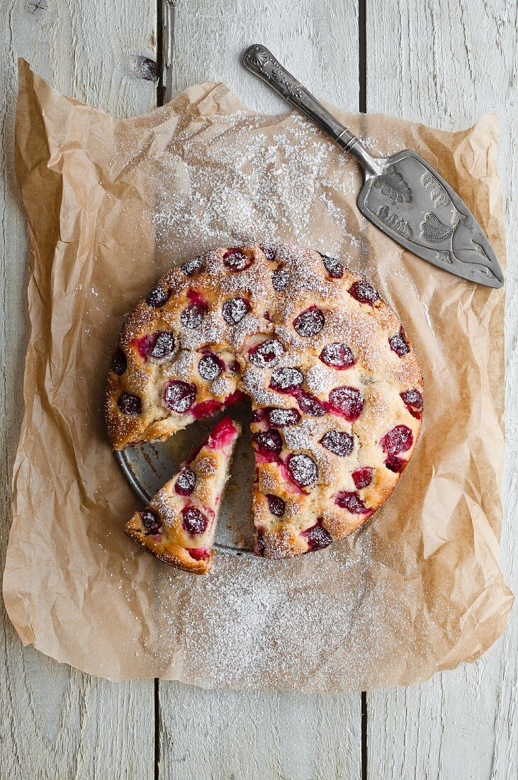 A whole plum cake, sliced, on a piece of baking paper