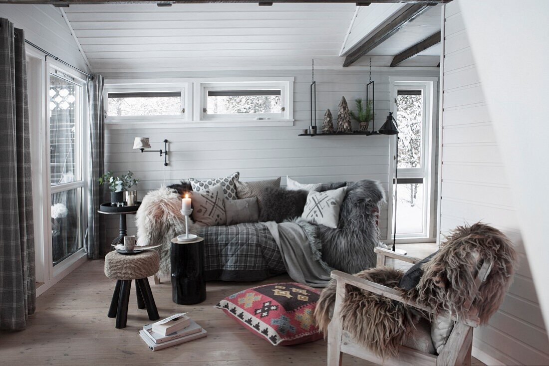 Fur rug on armchair and comfortable sofa in wood-clad interior