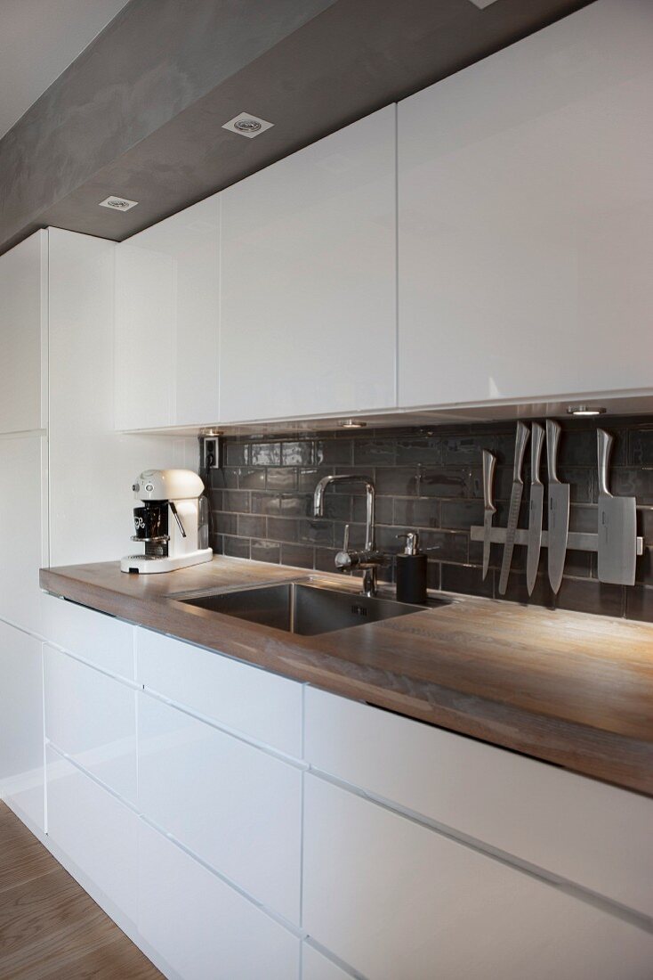 Modern industrial-style kitchen with white glossy fronts and wooden worksurface
