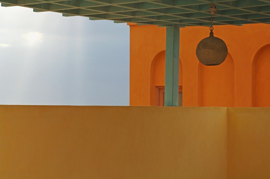 Hängeleuchte in orientalischem Stil an Pergola Kassettendecke, im Hintergrund orangefarbenes Haus