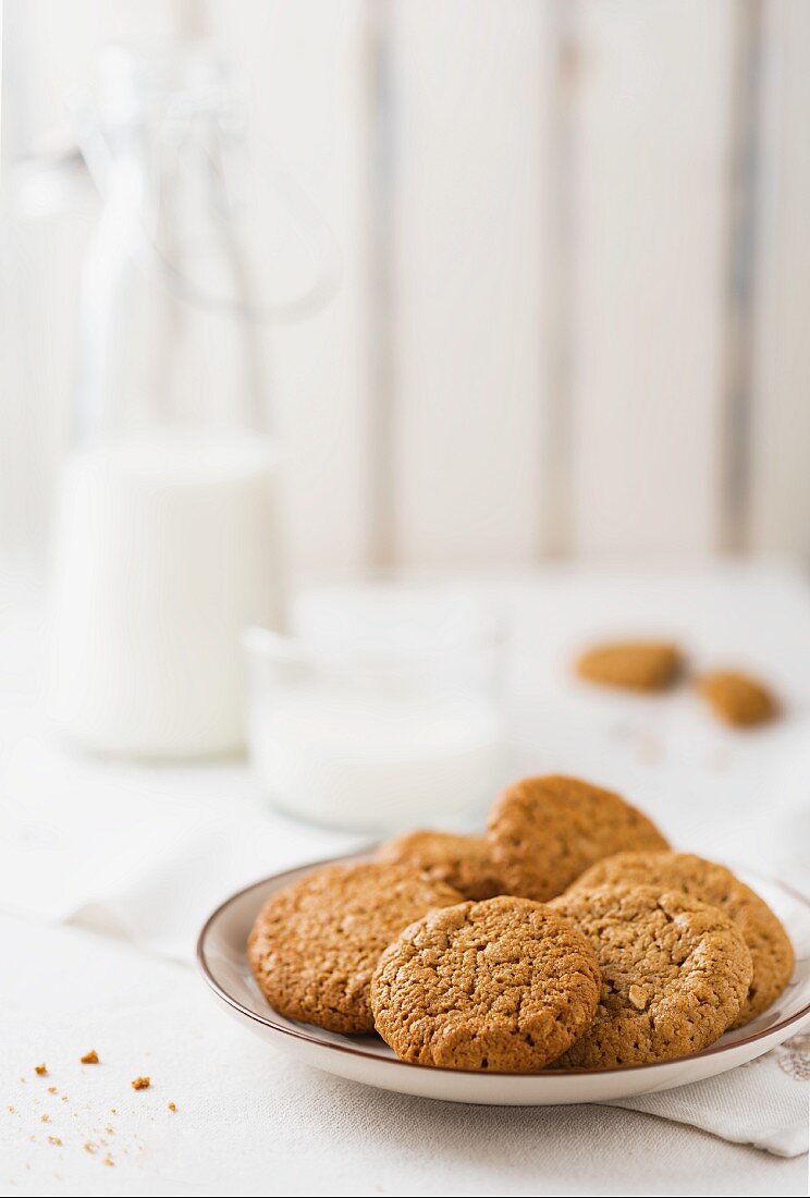 Oat biscuits on a plate with a glass and a bottle of milk in the background