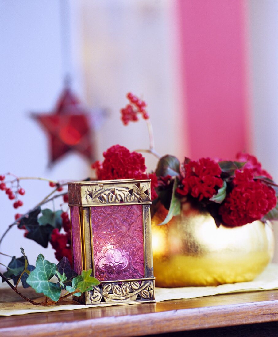 Tealight in miniature lantern and flower arrangement in gilt vase