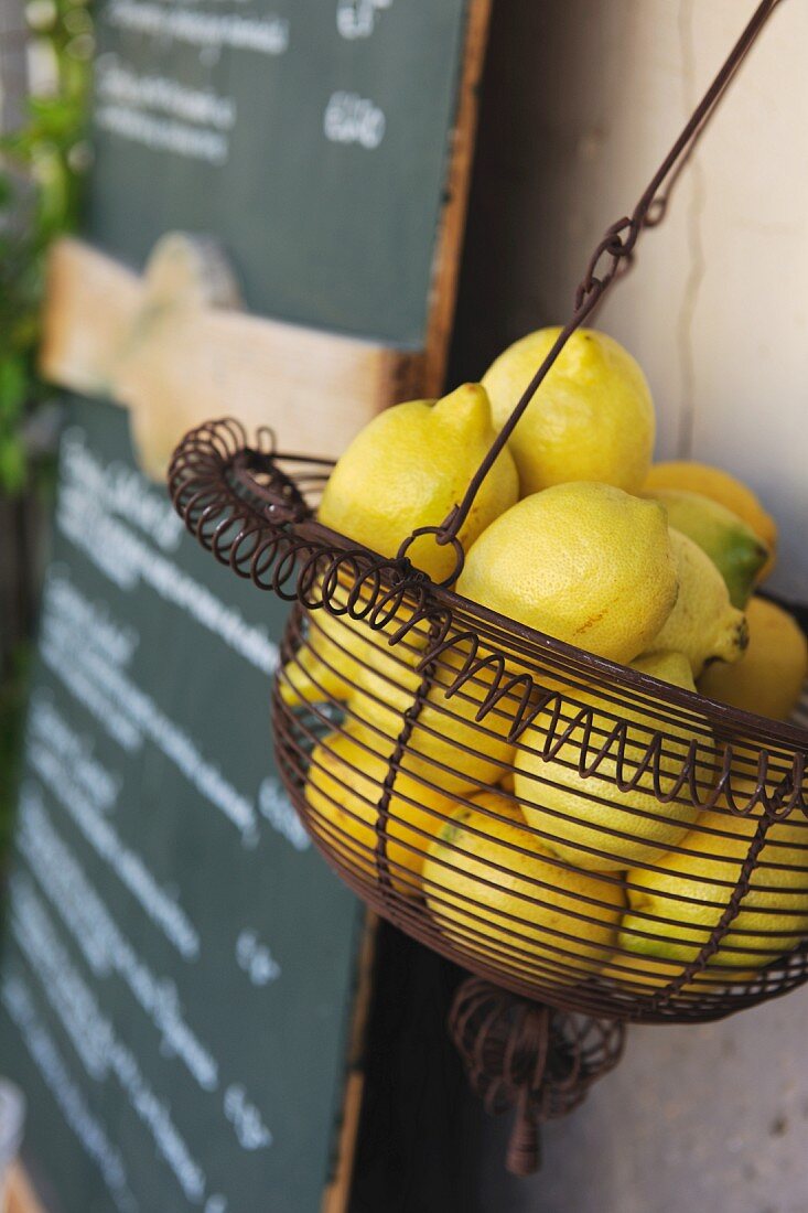 A wire basket of lemons next to a specials board in a bistro