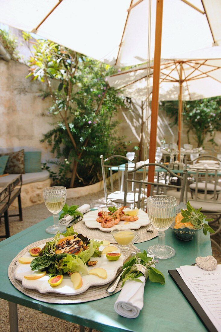 Gedeckte Tische unter Sonnenschirmen in mediterranem Innenhof