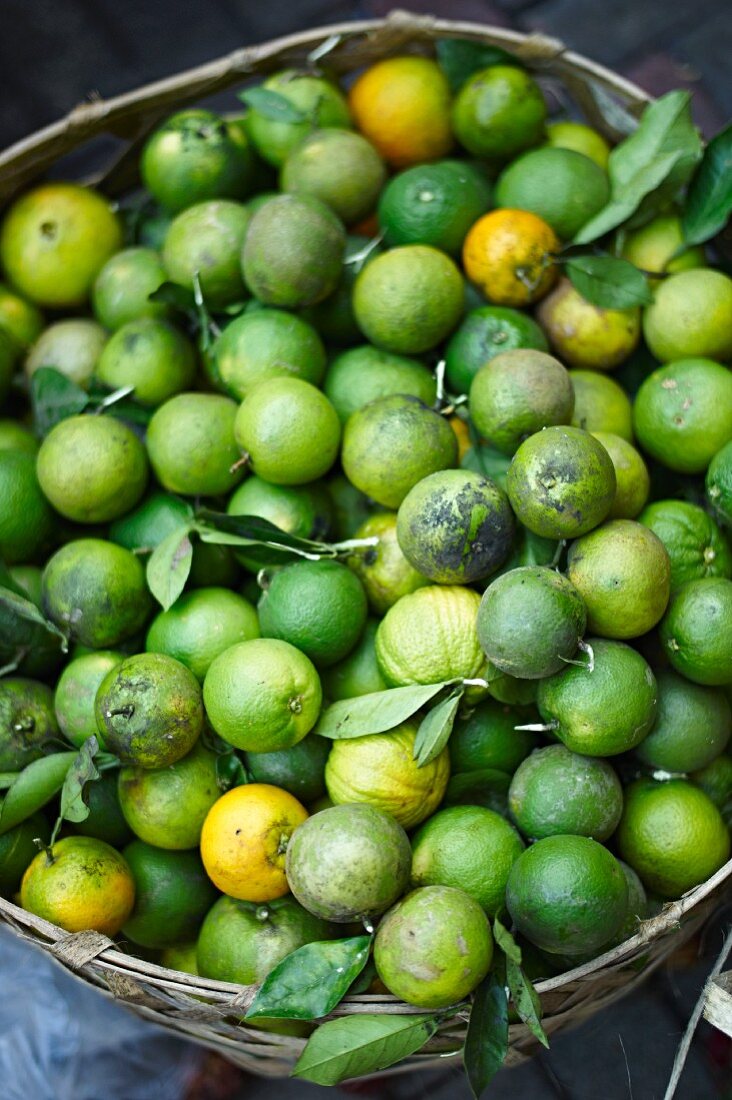 Green oranges in a basket at a market