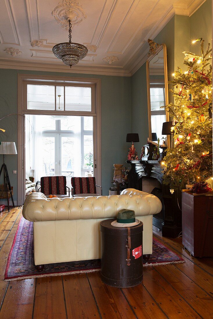 Christmas tree lit with fairy lights, stucco ceiling and Chesterfield sofa in living room