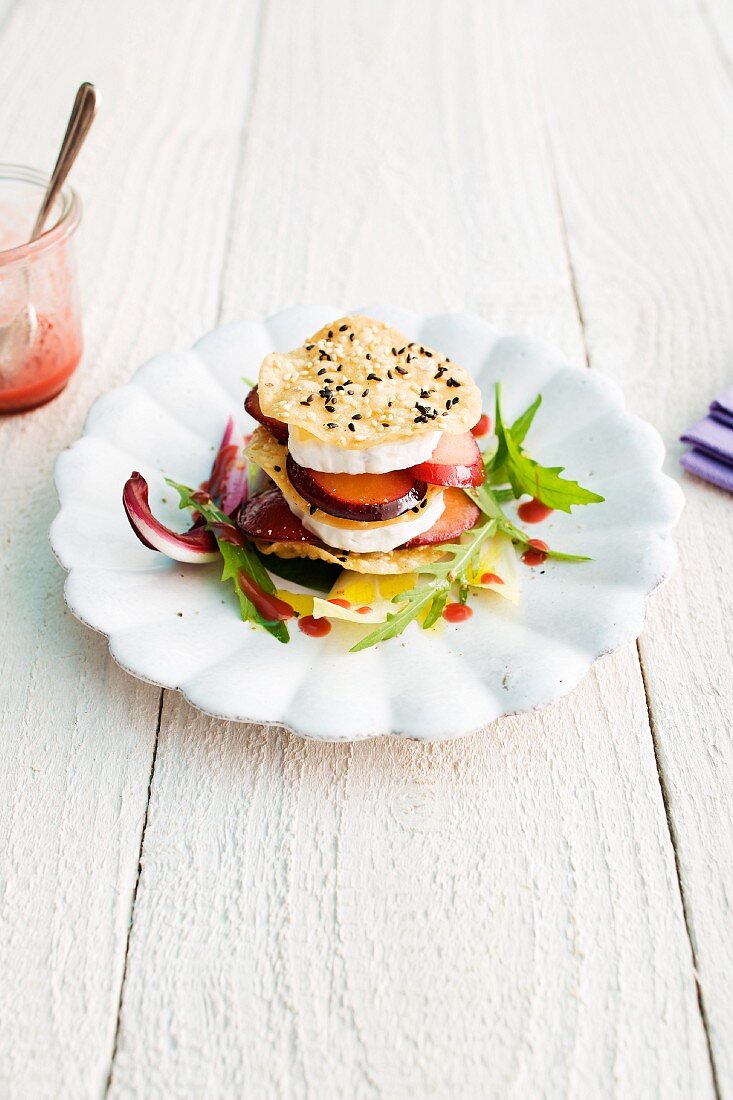 A cheese and plum tower with crispy sesame seed chips