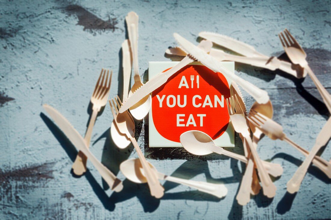 Schild mit Aufschrift: All you can eat, umgeben von Besteck