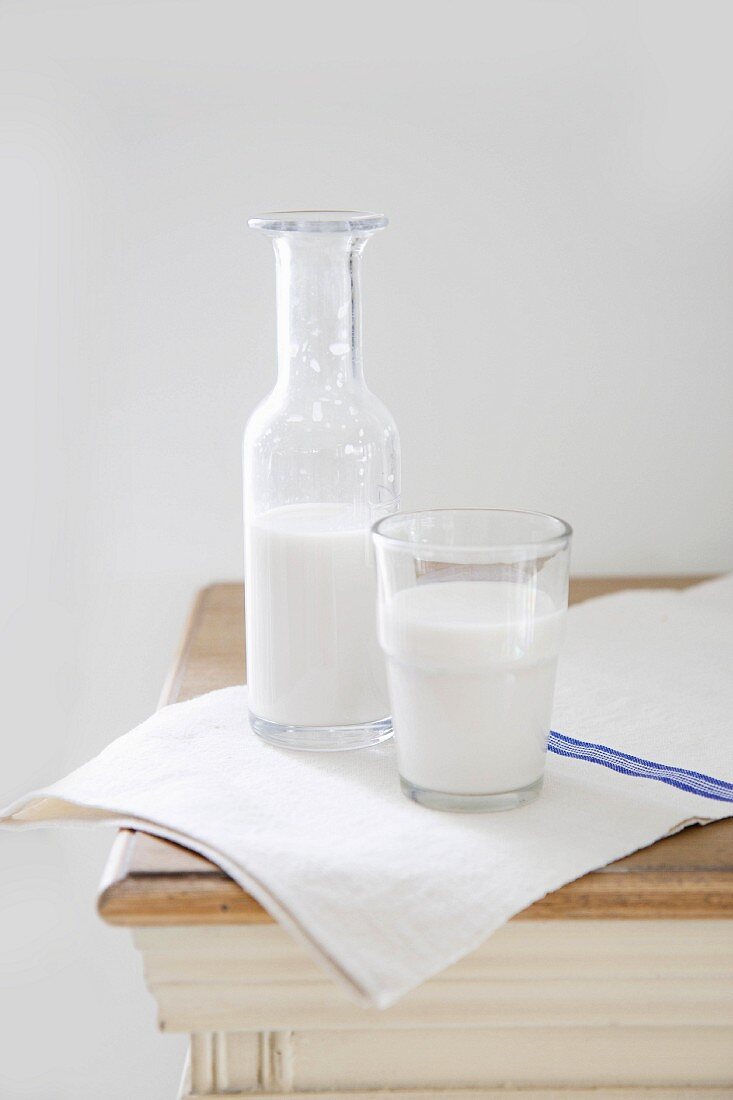 Almond milk in a glass and a bottle on a wooden table