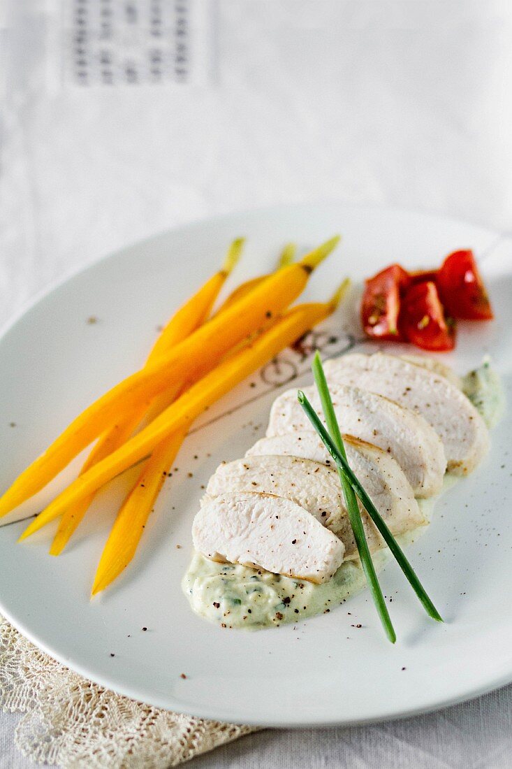 Steamed chicken breast with carrots on a creamy avocado sauce