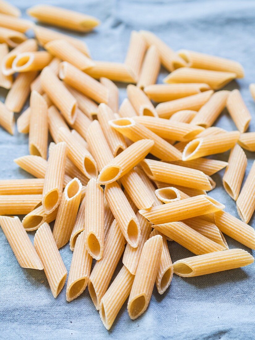 Wholemeal penne pasta on a blue cloth
