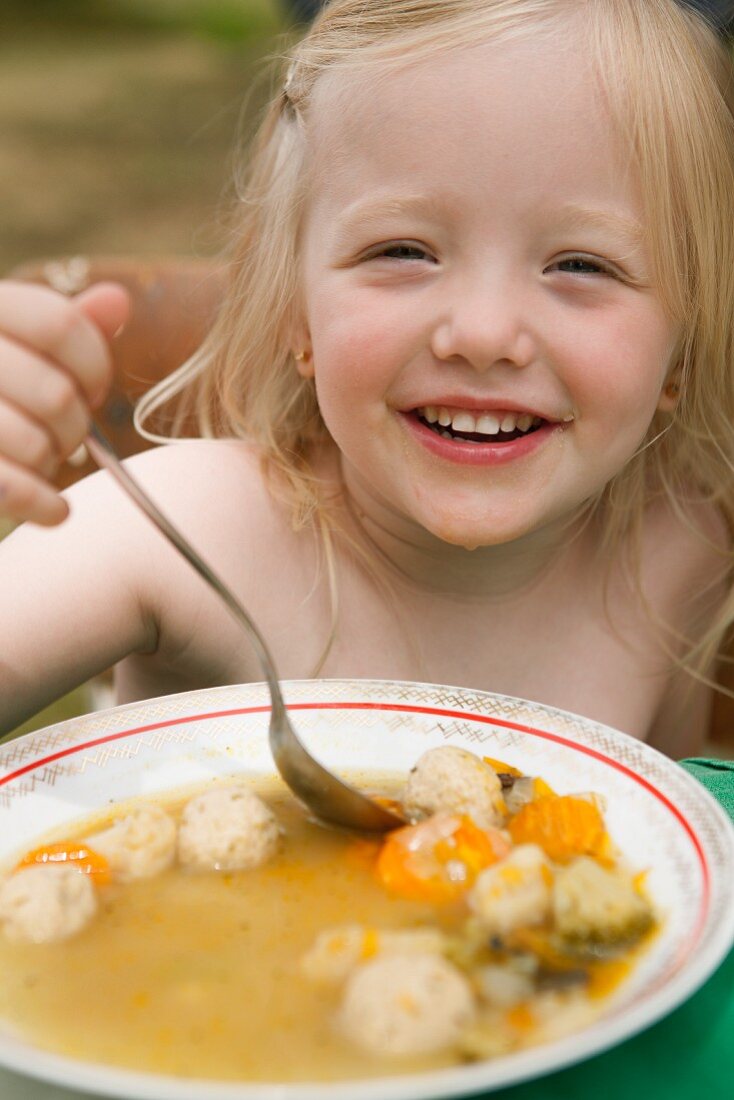 Kleines Mädchen isst Gemüsesuppe mit Hefeklösschen